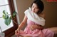 A woman in a pink dress sitting on a window sill.