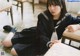 A woman in a school uniform sitting on a chair.