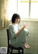 A woman sitting on a chair holding a glass of water.