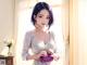 A woman in a white dress holding a purple purse.